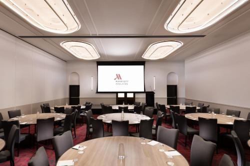 a conference room with tables and chairs and a screen at Adelaide Marriott Hotel in Adelaide