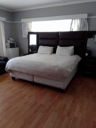 a large bed in a bedroom with a wooden floor at Tara's Terrace Guest House in King Williamʼs Town