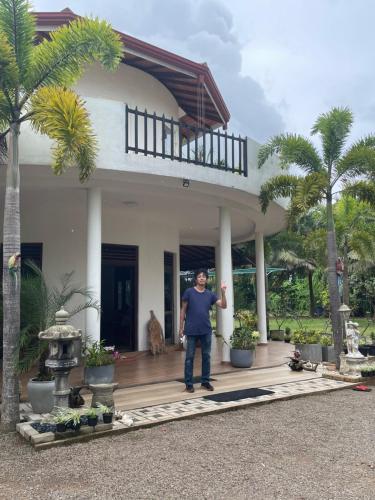 a man standing on the front porch of a house at Suzukis lagoon front in Katunayake