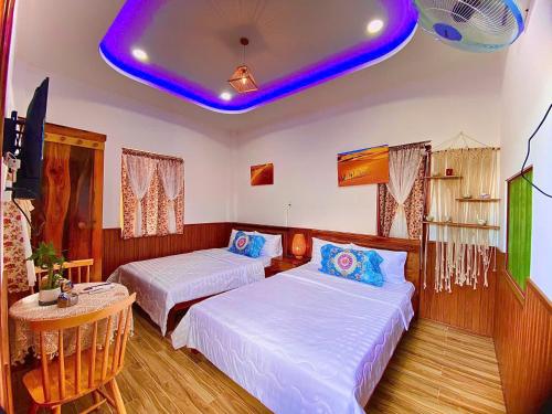 a hotel room with two beds and a blue ceiling at Sea-Breeze Homestay in Phan Thiet