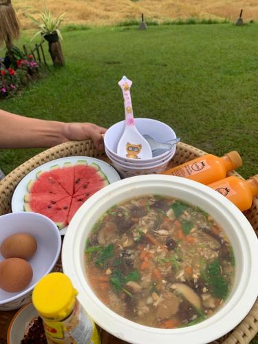een tafel met een kom soep en eten erop bij บ้านพักเคียงนา in Ban Sop Mae Klang