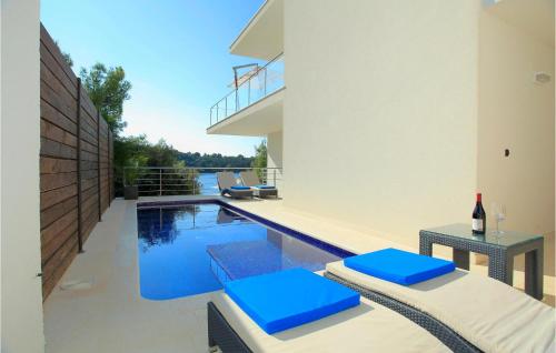 a swimming pool with blue cushioned chairs next to a house at Six-Bedroom Holiday Home In Karbuni in Prizba