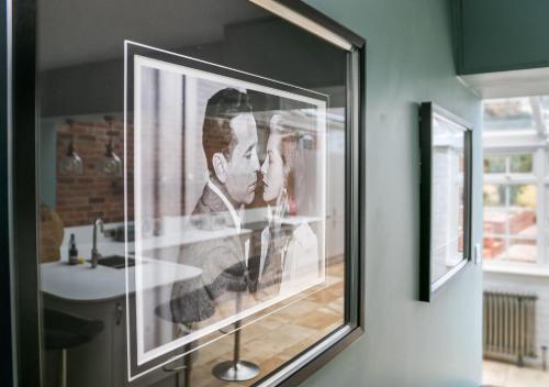 a framed picture of a couple on a wall next to a sink at Lodge Farm - Stunning 3 Bed with Large Garden! in Beckley