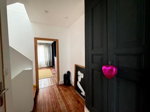 a hallway with a black door with a pink heart on it at Maison 3 étages en centre-ville in Laon