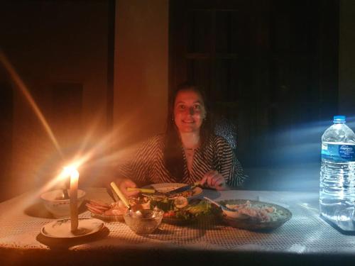 a woman sitting at a table with a candle and food at Chao Beach Villa in Ahangama