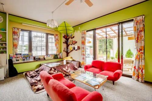 a living room with red furniture and green walls at Guesthouse Murabito in Yamanakako