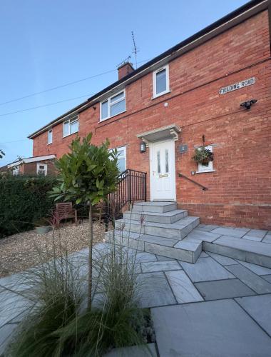 a red brick building with a white door and stairs at Red Brick House in Yeovil