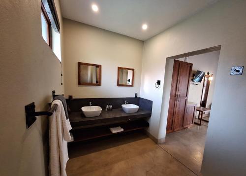 a bathroom with two sinks and a large mirror at La Lechere Guest House in Phalaborwa