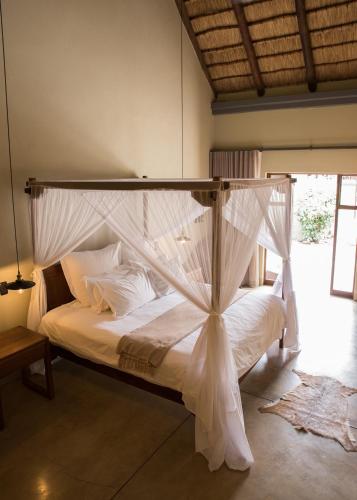 a bedroom with a canopy bed with white sheets and pillows at La Lechere Guest House in Phalaborwa