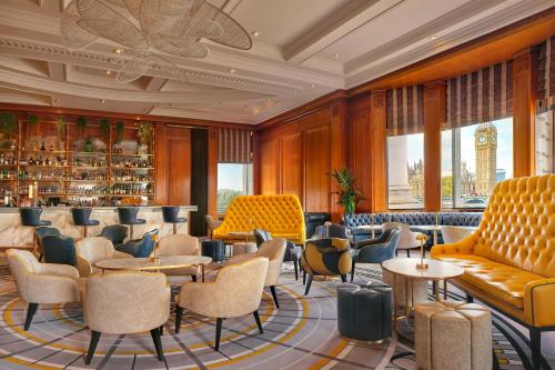 a lobby with chairs and tables and a bar at London Marriott Hotel County Hall in London