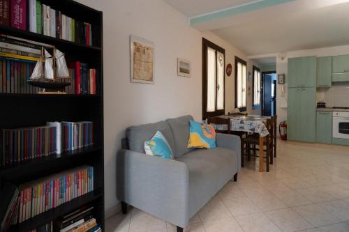 a living room with a couch and a book shelf with books at Risi & Bisi - il nostro rifugio in Chioggia