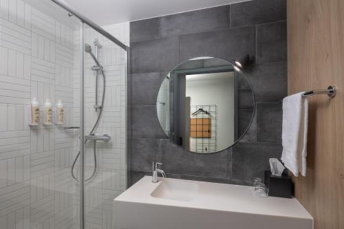 a bathroom with a sink and a shower with a mirror at Moxy Cork in Cork