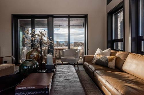 a living room with a brown couch and a window at Stuðlastrengur - Luxury private villa in Selfoss