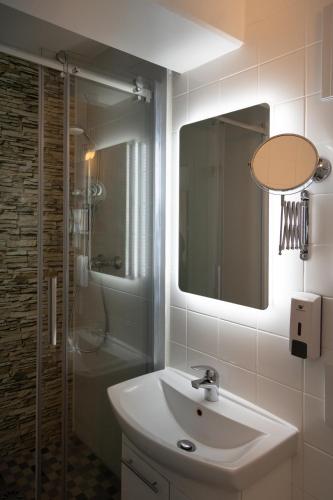 a bathroom with a sink and a shower and a mirror at Hotel Pankow in Berlin