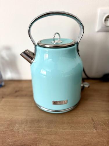 a blue slow cooker sitting on a wooden table at Apartment Hotel STUD MB in Ostrava