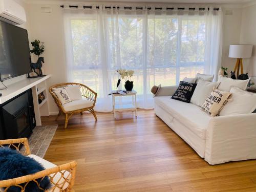 a living room with a white couch and a tv at Glenview Park Cottage and Farm Stay, Yarra Glen in Yarra Glen