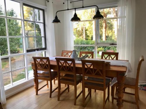 a dining room with a table and chairs and windows at Glenview Park Cottage and Farm Stay, Yarra Glen in Yarra Glen