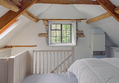 an attic bedroom with a bed and a window at Mill House Cottage - Star Stay on The Cotswold Way in Harescombe