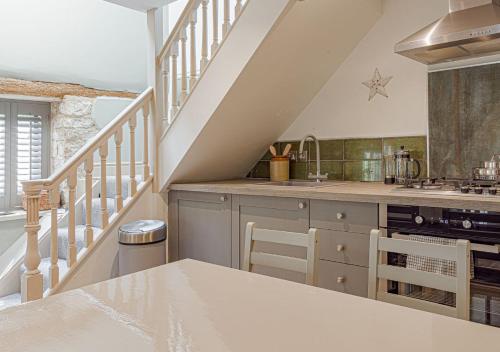 a kitchen with a counter top and a staircase at Mill House Cottage - Star Stay on The Cotswold Way in Harescombe