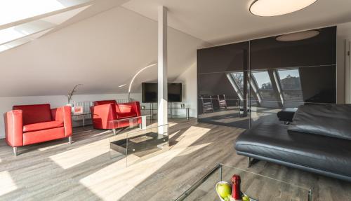 a living room with black leather furniture and red chairs at Raum in Ostseebad Koserow