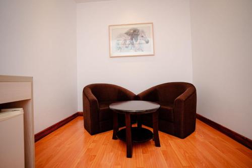 a chair and a stool in a room at Royal Raj Hotel in Rājshāhi