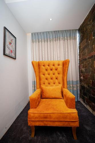 an orange chair sitting in front of a window at Royal Raj Hotel in Rājshāhi