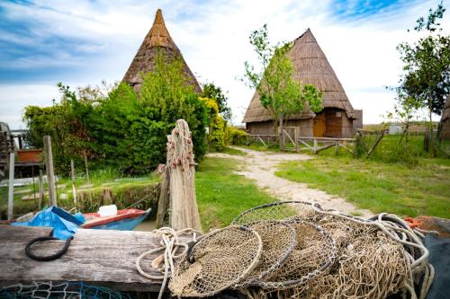 a boat tied to a dock with two thatch roofs at Ferrari Apartments Panorama Sea View in Caorle