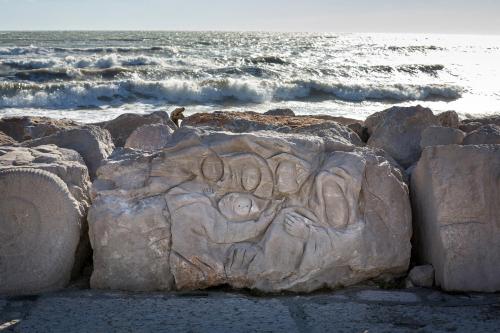 a rock with a carving on it next to the ocean at Ferrari Apartments Panorama Sea View in Caorle