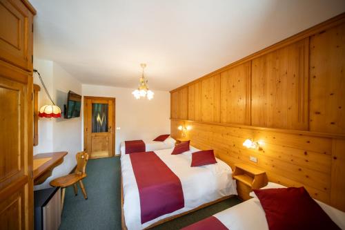 a hotel room with two beds and a desk at Hotel il Cardo in San Vito di Cadore