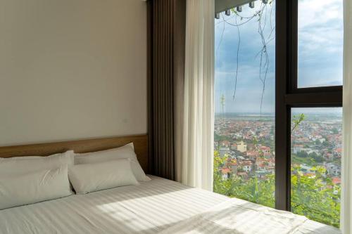 a bed in a room with a large window at Luffy Home căn hộ xinh Ecopark có bồn tắm và vườn cây ngắm Hoàng hôn in Kim Quan