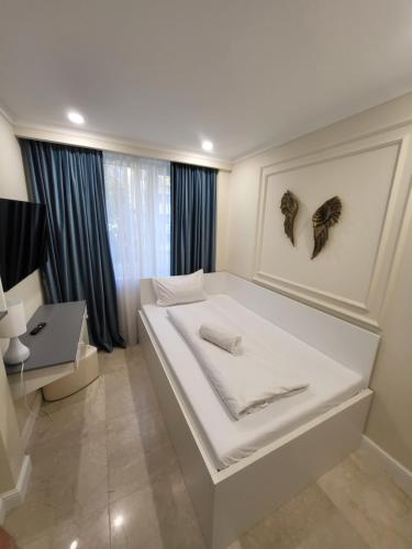 a white bedroom with a large bed and a desk at Sika DeLuxe Apartment Arad in Arad