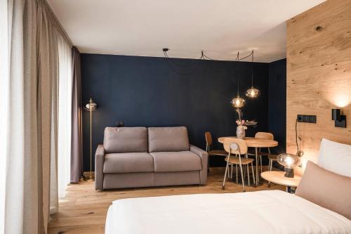 a bedroom with a bed and a couch and a table at The Post Mountain Residence in Dobbiaco