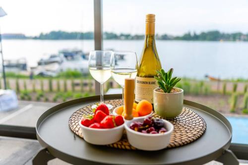 a table with a bottle of wine and a bowl of fruit at Marina Ostróda II - najlepszy widok w Ostródzie in Ostróda