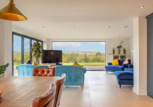 a living room with blue furniture and a large window at Orchard Barn - Luxury 4 BD Barn Conversion! in Fladbury