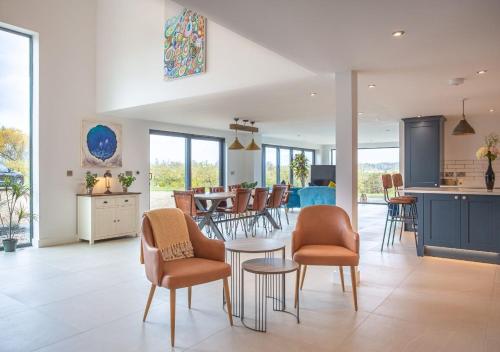 a kitchen and living room with chairs and a table at Orchard Barn - Luxury 4 BD Barn Conversion! in Fladbury