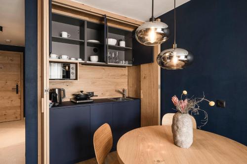 a kitchen with blue walls and a wooden table at The Post Mountain Residence in Dobbiaco
