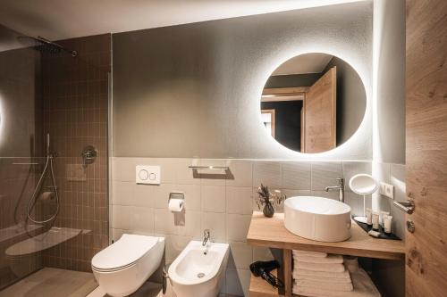 a bathroom with a sink and a toilet and a mirror at The Post Mountain Residence in Dobbiaco