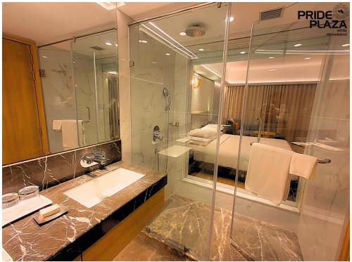 a bathroom with a glass shower and a sink at Pride Plaza Hotel, Ahmedabad in Ahmedabad