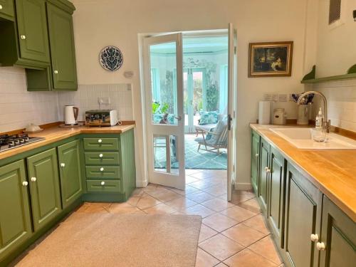 a kitchen with green cabinets and a door to a patio at Gorgeous cottage in Nantwich