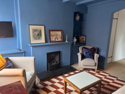 a living room with blue walls and a fireplace at Gorgeous cottage in Nantwich