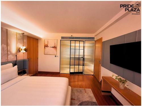 a hotel room with a bed and a flat screen tv at Pride Plaza Hotel, Ahmedabad in Ahmedabad