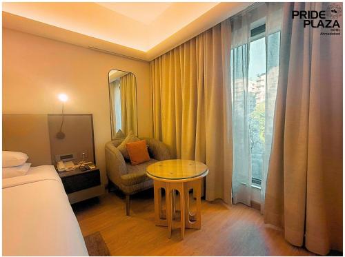 a hotel room with a table and a chair and a window at Pride Plaza Hotel, Ahmedabad in Ahmedabad