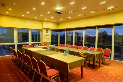 a conference room with long tables and chairs and windows at Viešbutis Banga in Tauragė