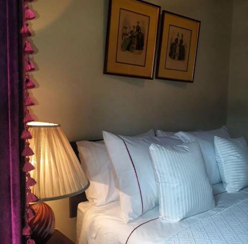 a bedroom with a bed with white pillows and a lamp at A Hotel Boutique Pelluhue in Pelluhue