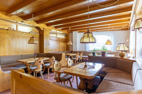 a restaurant with couches and tables and chairs at Hotel il Cardo in San Vito di Cadore
