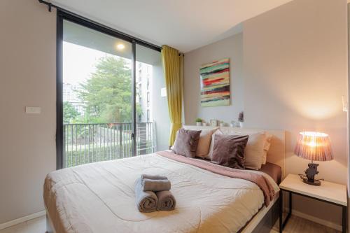 a bedroom with a bed and a large window at Nimman Soi 5, Chiang Mai in Chiang Mai