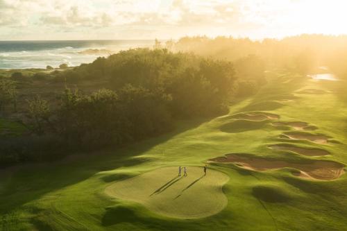 an overhead view of a golf course with two people on the green at The Ritz-Carlton O'ahu, Turtle Bay in Kahuku