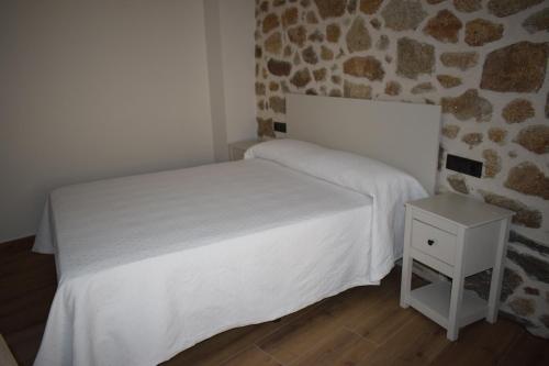 a bedroom with a white bed and a stone wall at Alojamiento Rural La Josefa de los Arribes in Fermoselle