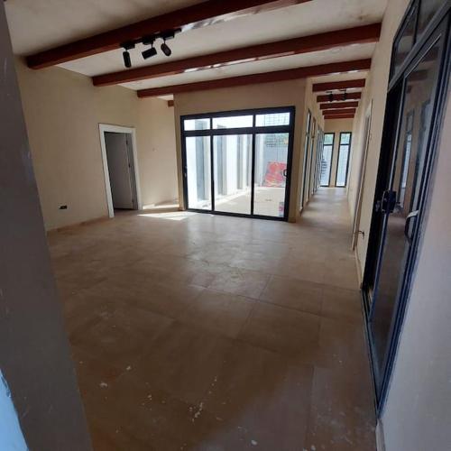 a large empty room with a large glass door at Palm Breeze Villa in Sambuya