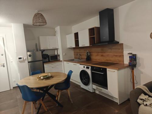 a small kitchen with a table and a table and chairs at F2 cosy avec jardin in Saint-Louis